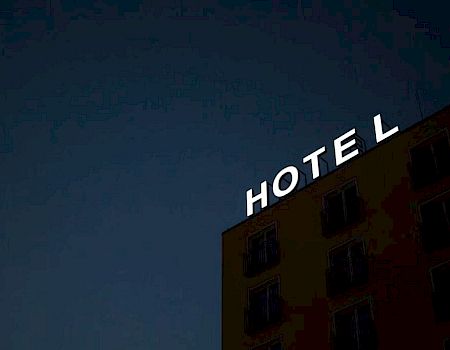 A building with a neon sign reading "HOTEL" against a dark sky.