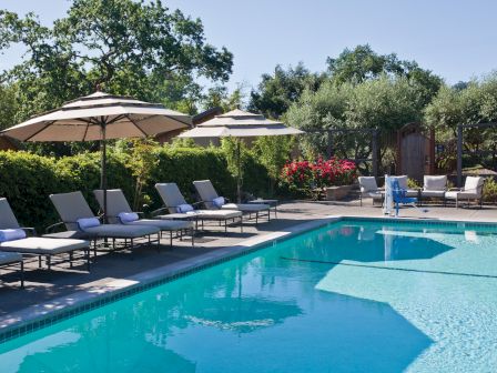 A swimming pool area with lounge chairs, umbrellas, and surrounding greenery, providing a serene and inviting atmosphere.