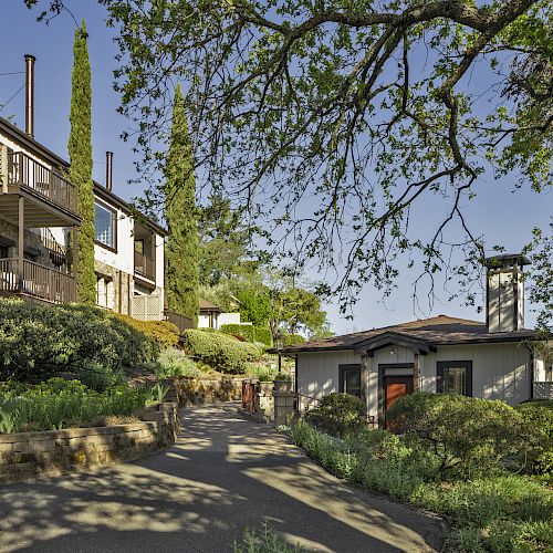 The image shows a peaceful outdoor setting with two houses surrounded by lush greenery and trees, with a clear path between them ending the sentence.